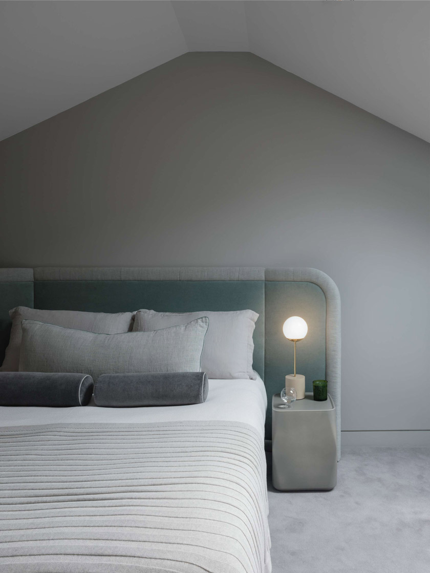 Contemporary Bedroom with Vaulted Ceiling: A serene bedroom with a vaulted ceiling, a bed with gray and teal accents, and a modern nightstand with a minimalist lamp. The room is decorated in soft, neutral tones.