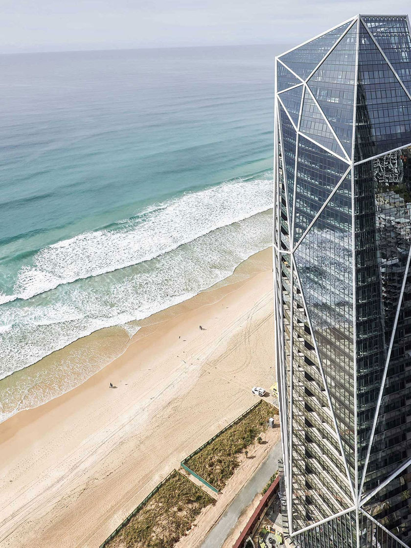 The exterior view of the Jewel development on the Gold Coast, featuring a modern high-rise building with geometric designs and the expansive beach below.