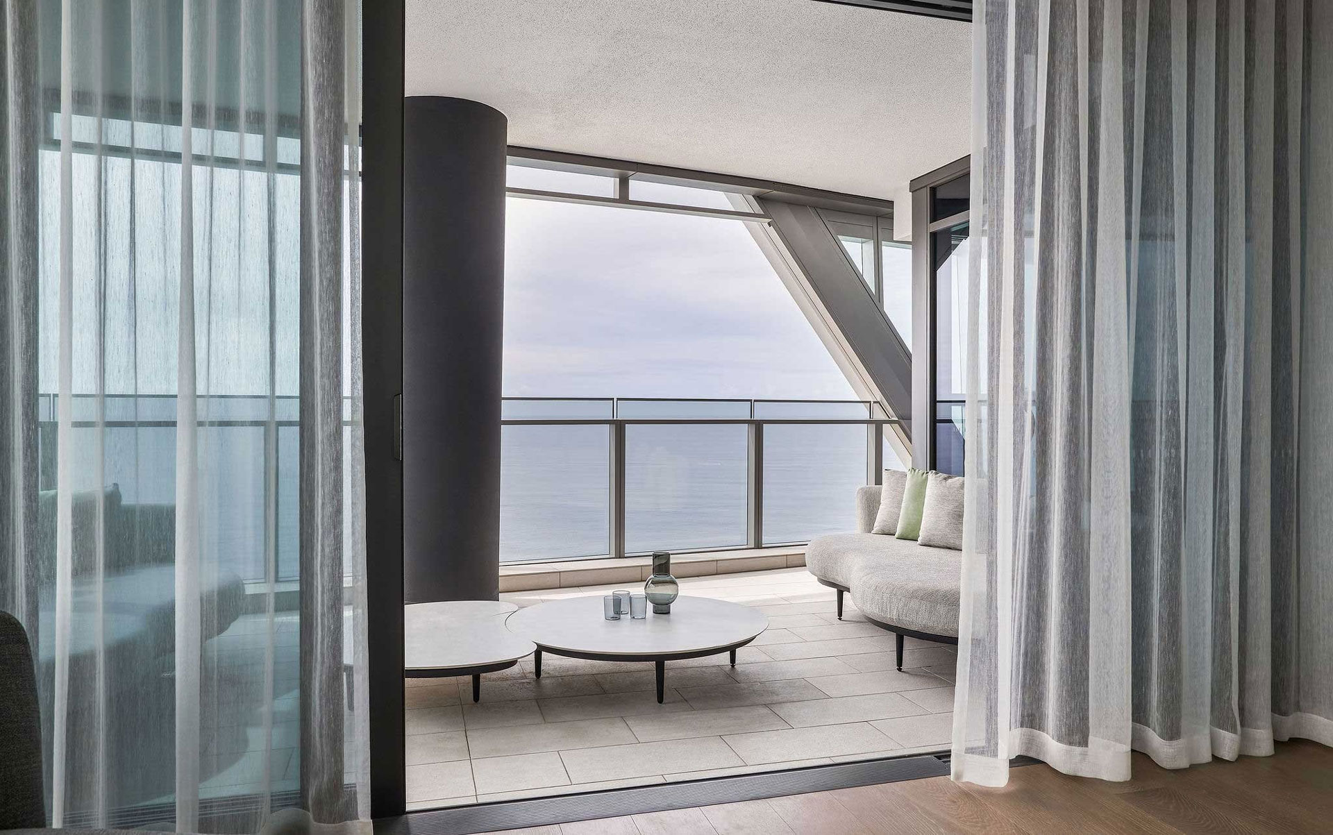 A view from the Jewel Apartment's balcony designed by Nina Maya Interiors, showcasing a round coffee table and seating with unobstructed views of the ocean.