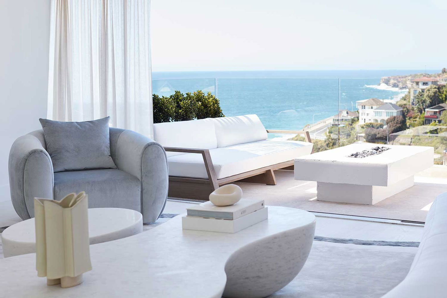 Photo taken from the living room over the balcony overlooking Tamarama, featuring an ocean view and outdoor seating. Interior design by Nina Maya Interiors for the Cove House in Tamarama.