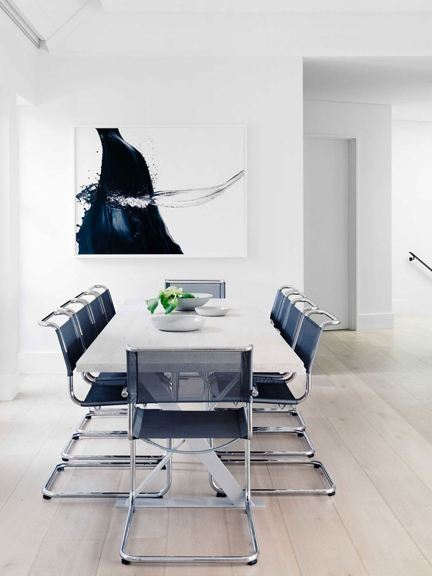 Ocean Pearl Villa - Palm Beach: A minimalist dining area with a white dining table, black chairs, and a striking abstract painting on the wall, designed by Nina Maya Interiors.