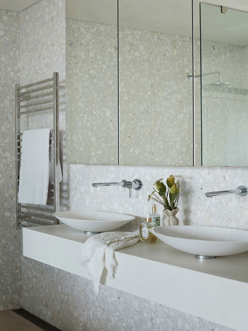 Modern bathroom with dual sinks, terrazzo walls, and a large mirror, designed by Nina Maya Interiors.