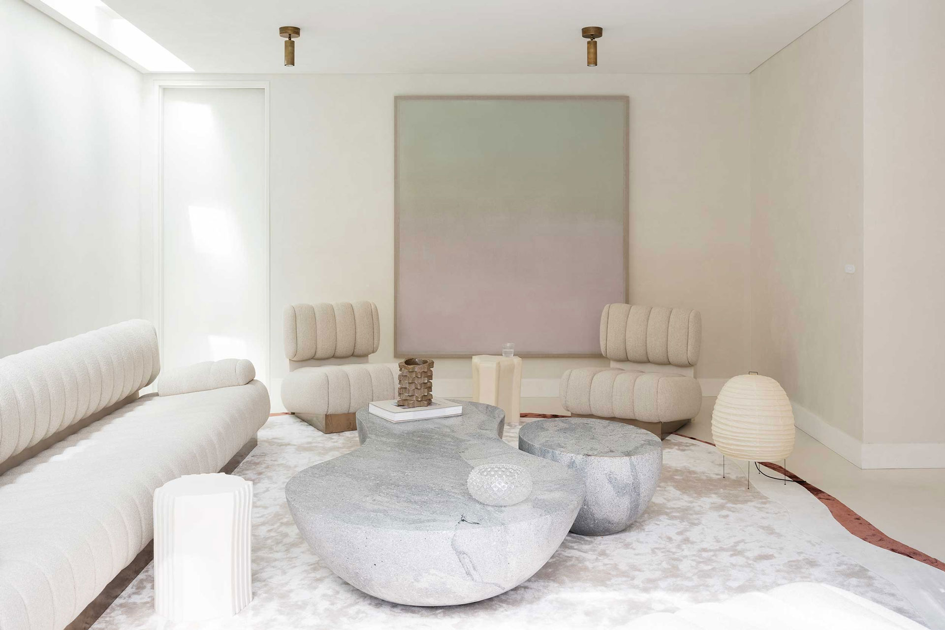 Modern living room featuring cream sofas, abstract art, and unique stone coffee tables, designed by Nina Maya Interiors.