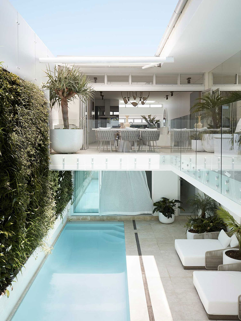 Indoor-outdoor living space with a pool, dining area, and lush greenery.