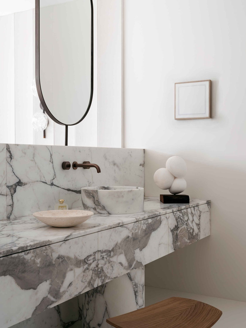 Close-up of the marble vanity in the bathroom, featuring a sleek mirror and minimalistic decor. Interior design by Nina Maya Interiors.