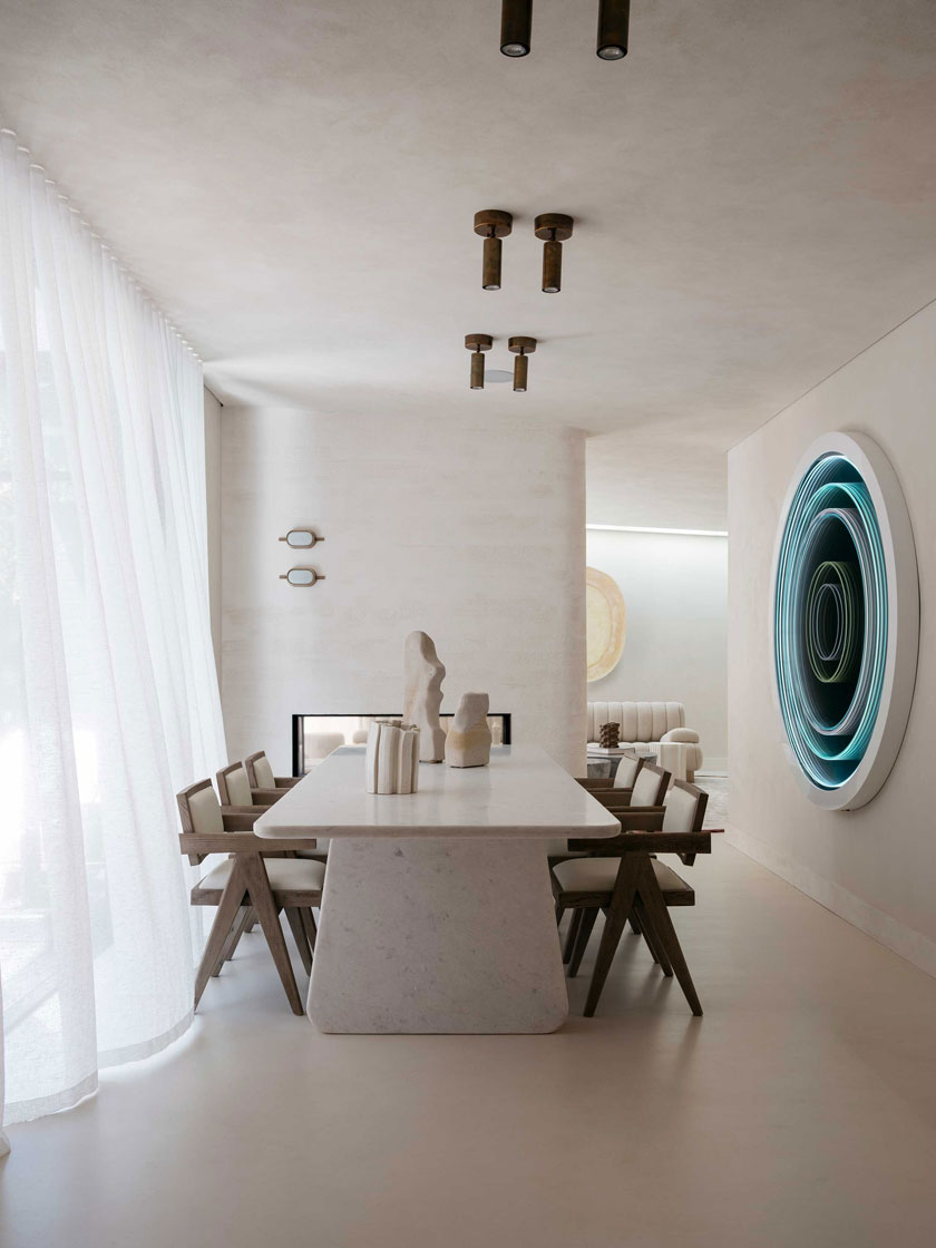 Dining room featuring a large white table, artistic decor, and soft lighting, designed by Nina Maya Interiors.