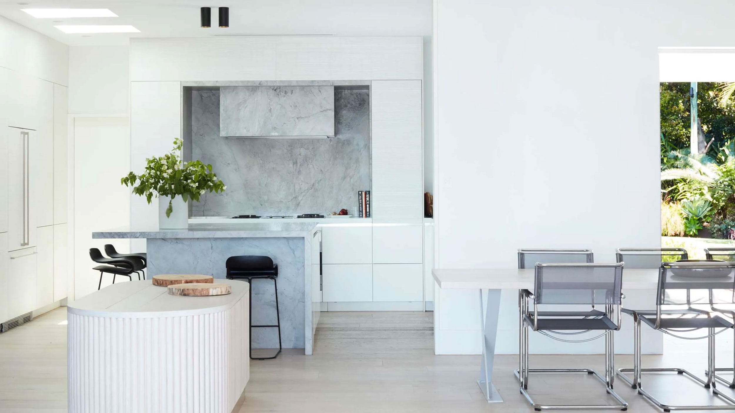 Ocean Pearl Villa - Palm Beach: Modern kitchen with white cabinetry, a central island with a grey stone countertop, and minimalist black bar stools, designed by Nina Maya Interiors.