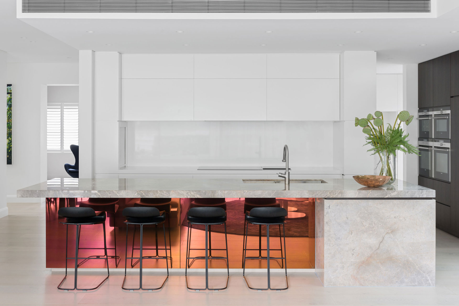 Sleek modern kitchen with white cabinets, a marble island, and black bar stools, designed by Nina Maya Interiors.