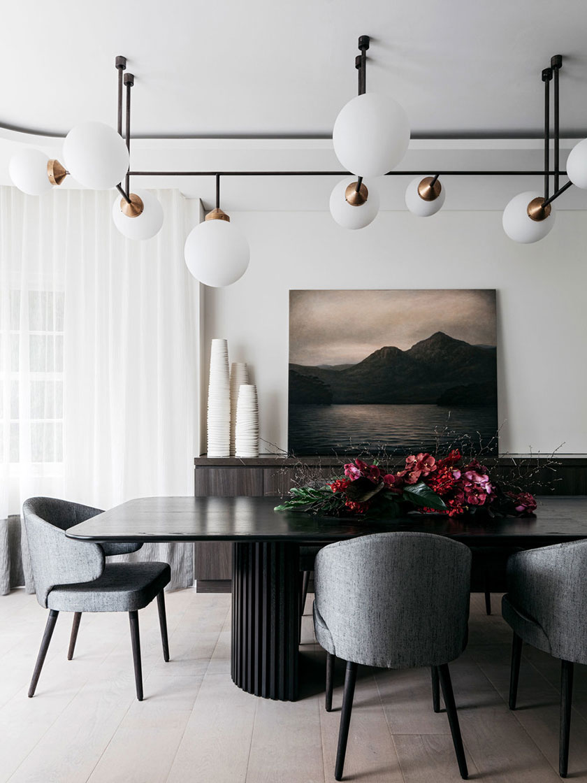 Stylish dining room featuring a dark wood table, grey chairs, and modern lighting fixtures, designed by Nina Maya Interiors.