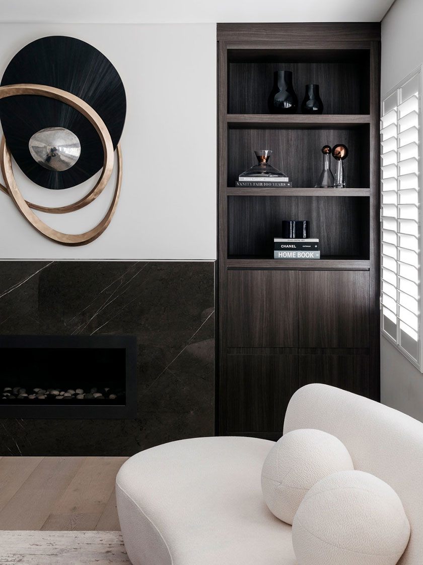 Living room decor details including dark wood shelving, artistic wall decor, and a white curved sofa, designed by Nina Maya Interiors.