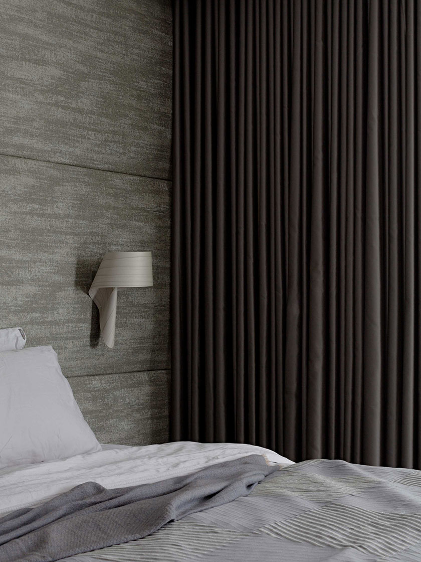 Sophisticated bedroom with grey textured walls, dark curtains, and a neatly made bed, designed by Nina Maya Interiors.