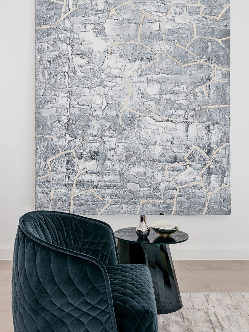 Close-up view of a blue textured chair and abstract wall art.