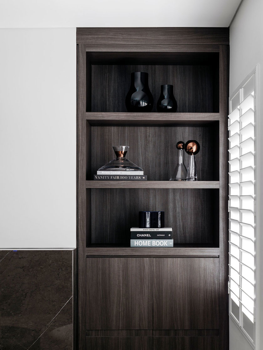 Dark wood shelving unit with black vases, books, and decorative glassware.