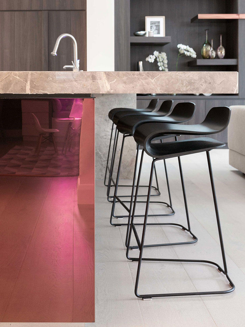 Contemporary kitchen bar area with a marble countertop, black bar stools, and reflective pink base, designed by Nina Maya Interiors.